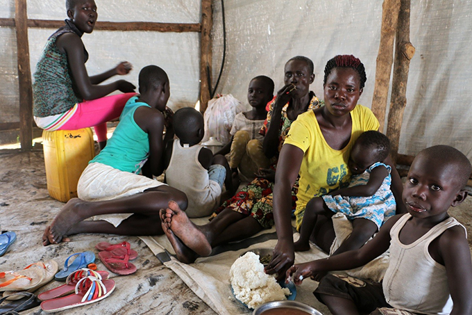 Susan, in yellow shirt, eats with her child and her neighbours in Shelter 11 at Imvepi. Photo and Story by WFP/Lydia Wamala
