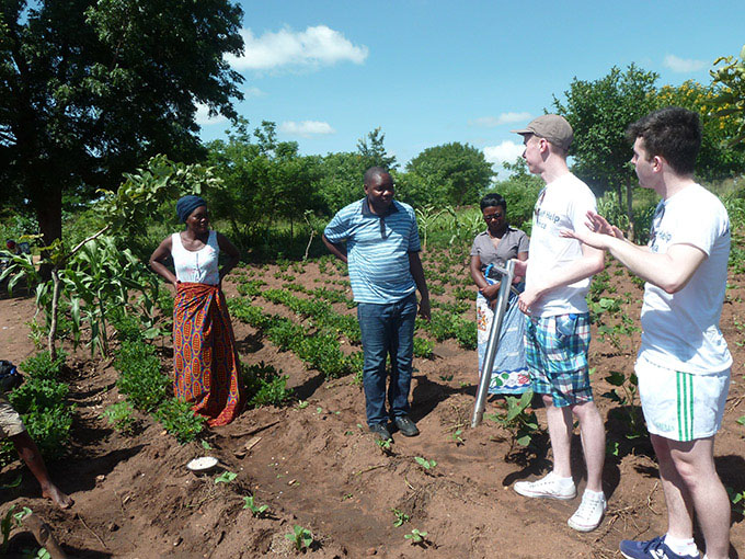 Diarmuid Curtin (right) and Jack O'Connor (left) field test their device on a field with local farmers, Kwitanda village, Balaka district, Malawi. (Credit: Self Help Africa)
